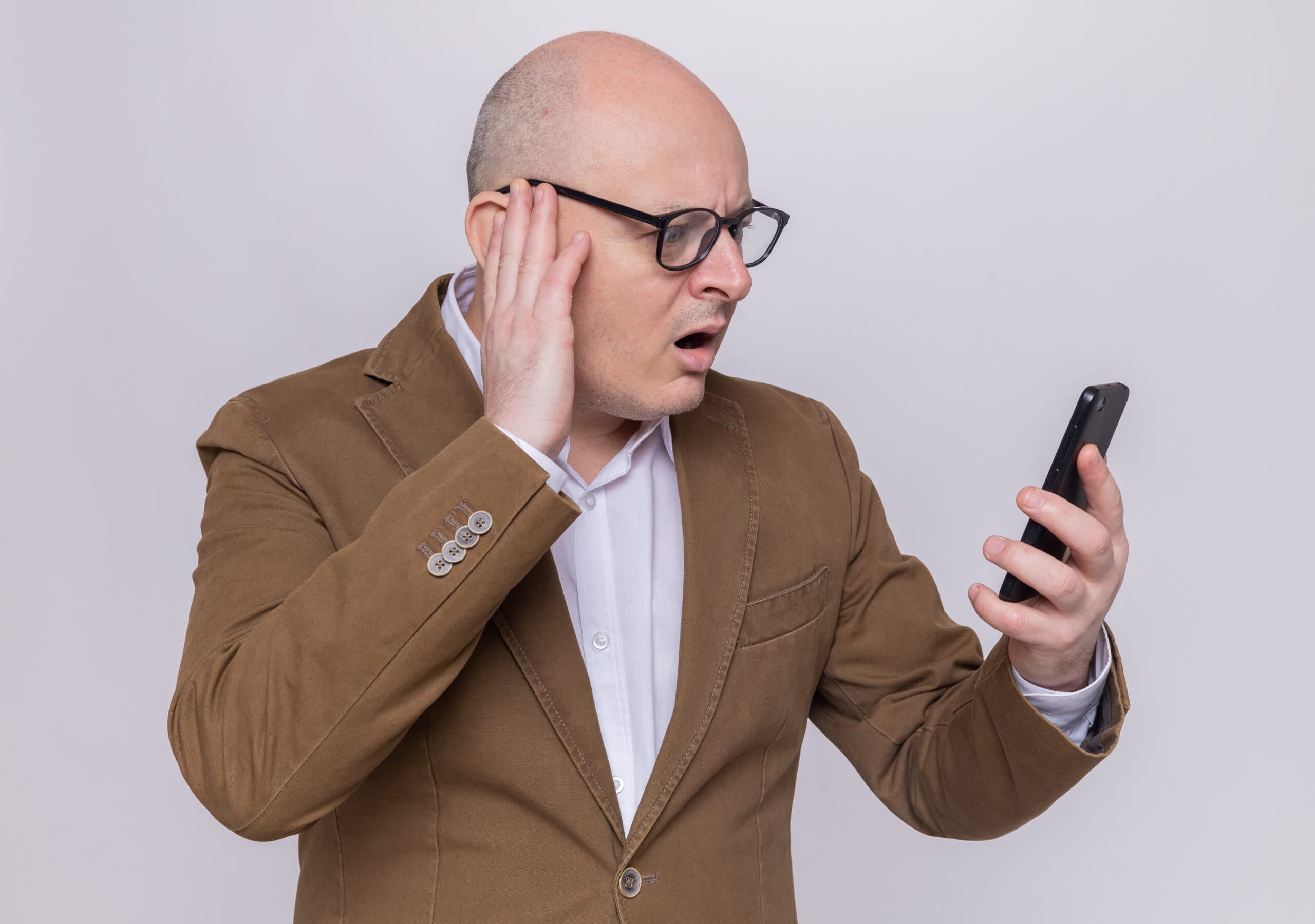 fake-profile erkennen ab50 - Überraschter Mann schaut schockiert auf sein Smartphone