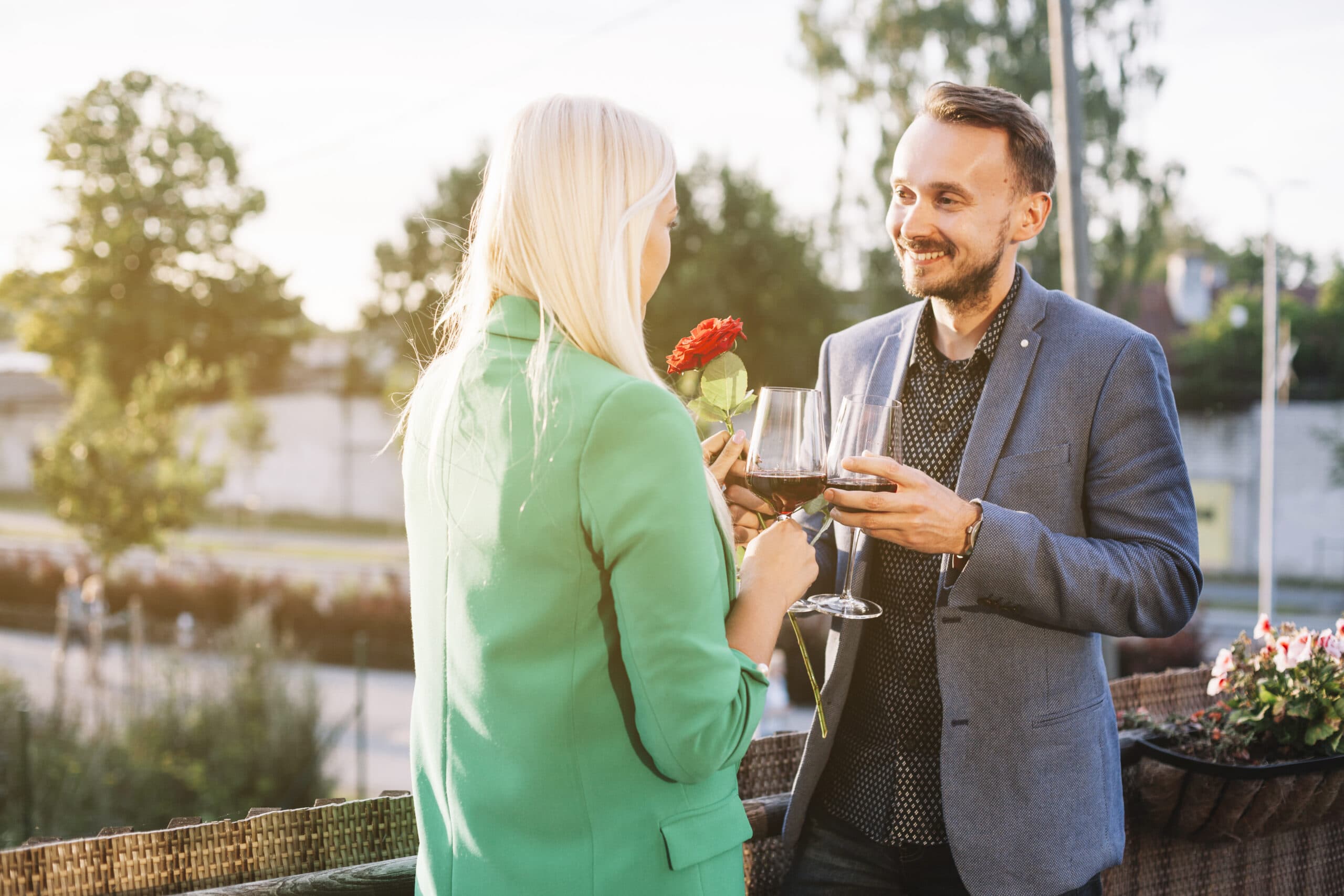Romantisches Paar ab 50 stößt mit Wein an und hält eine rote Rose. Nähe zulassen lernen – ohne Angst vor Verletzung